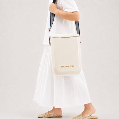 Pavilion Cooler by The Line Edit. - A cream cooler bag carried over the shoulder, featuring a branding logo and set against a neutral background.