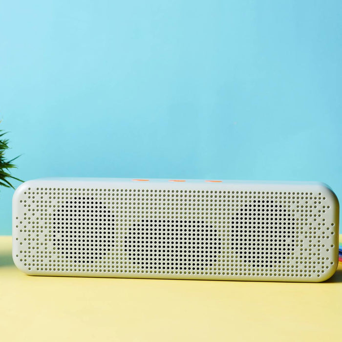 Modern wireless speaker placed elegantly with a potted plant and colorful stationery.