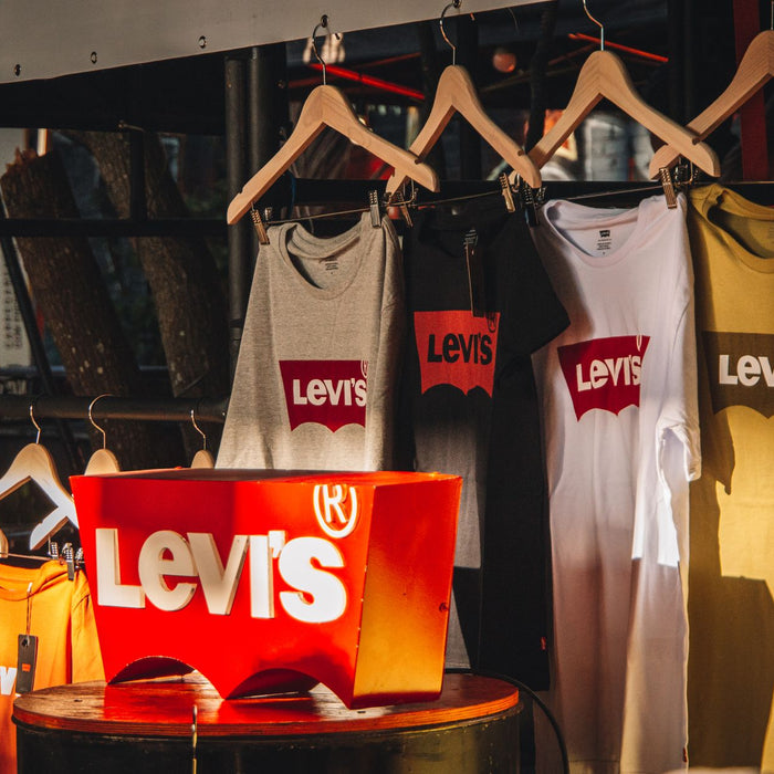 Vibrant display of Levis T-shirts hanging on wooden hangers in a sunlit store.