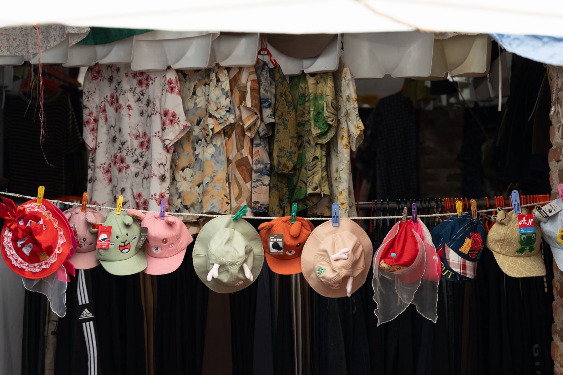 Vibrant display of hats and floral dresses at outdoor market, perfect for festivals.