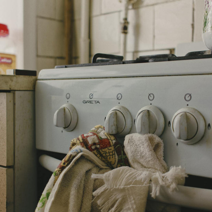 A vintage gas stove adorned with tea towels beside a kitchen counter, evokes nostalgia.