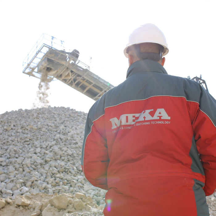 Back view of a construction worker in Ankara quarry observing a conveyor belt at a gravel site.