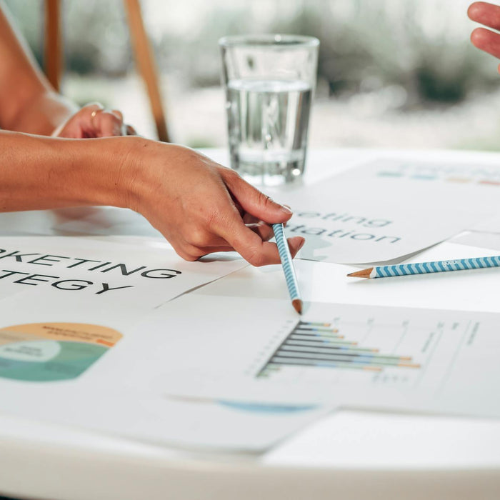 Hands discussing marketing strategy with charts in an office setting.