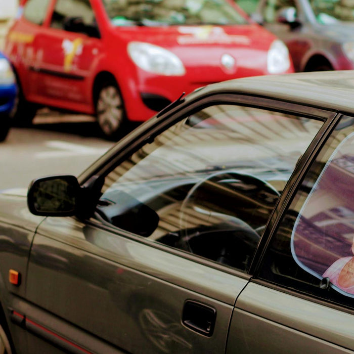 A close-up of cars parked on the street featuring a decorative sunshade with a royal image.