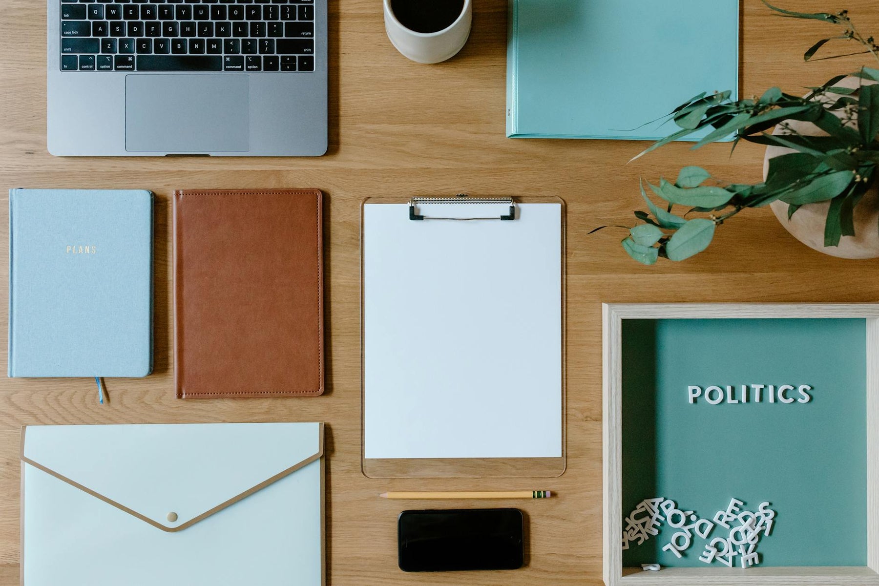 Stylish office supplies arranged neatly on a desk, including a laptop, clipboard, and notebooks.