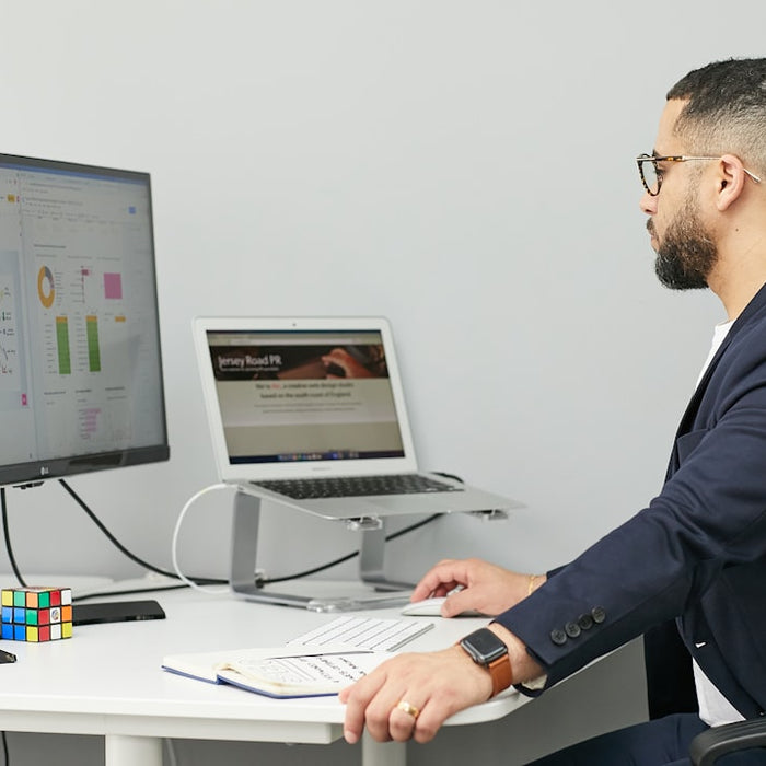 a man sitting at a desk with a laptop and a computer
