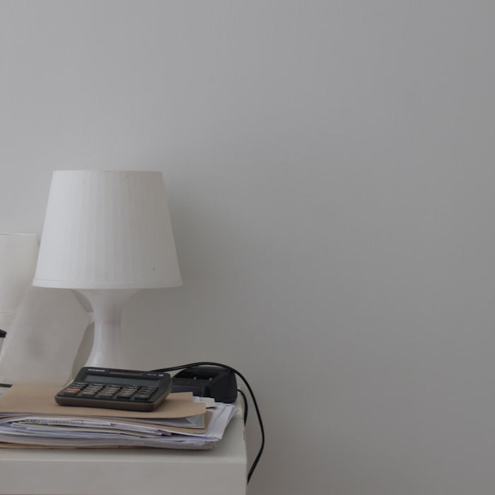 a white table topped with a lamp and a phone