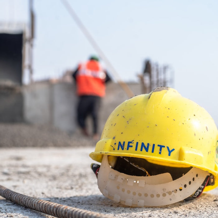 A yellow hard hat sitting on top of a cement ground