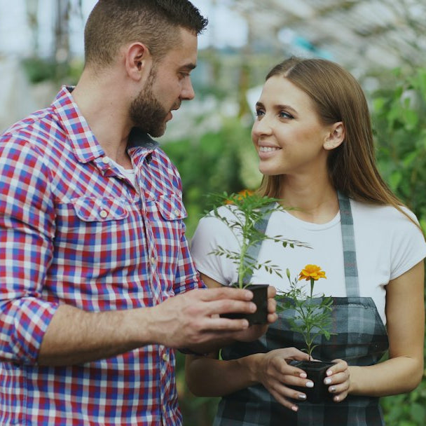 Couple holding potted plants in a garden center