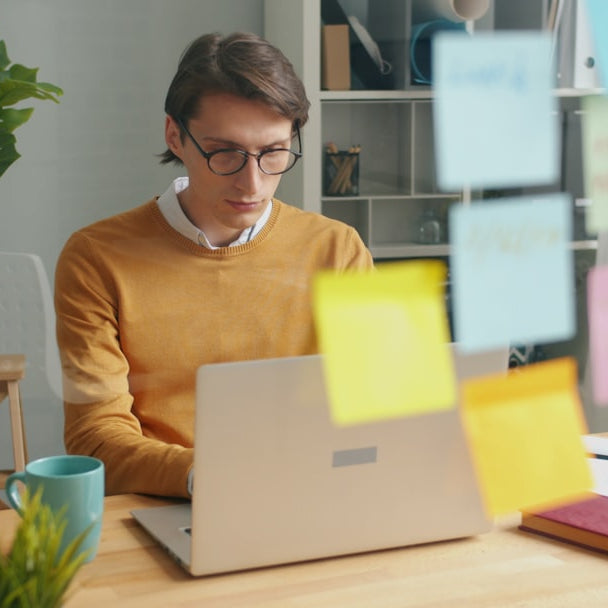 Man working on a laptop with sticky notes
