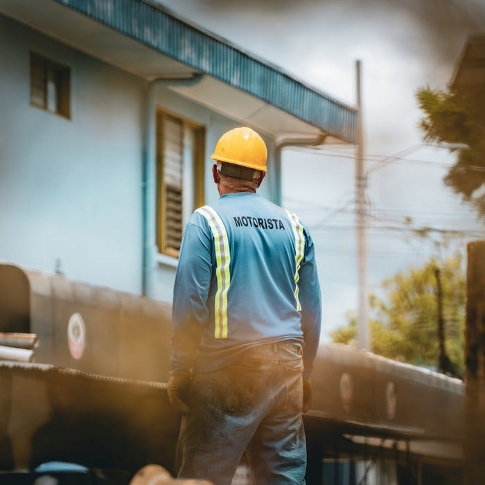 Worker in hard hat and safety vest looks away.