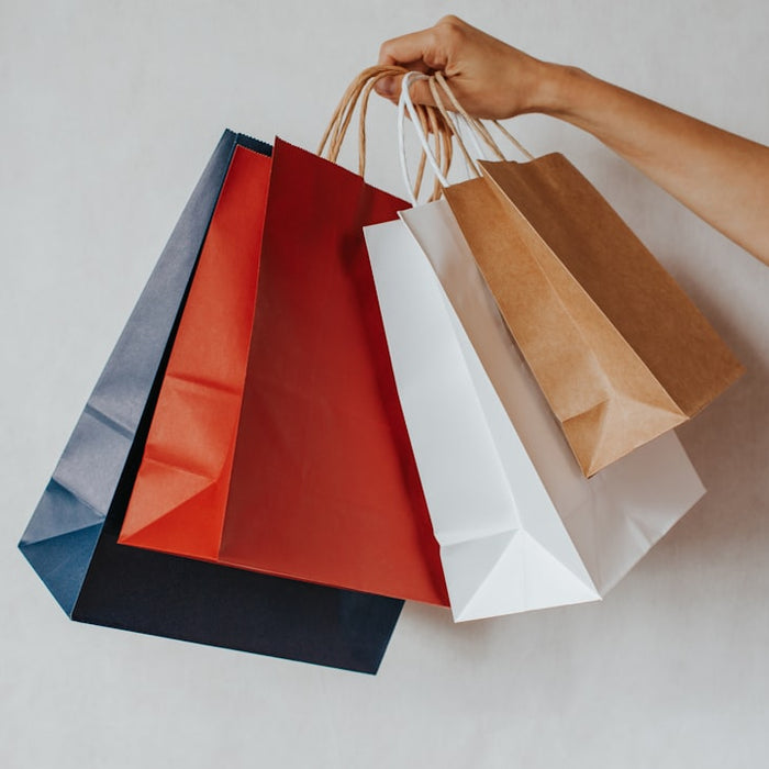 Hand holding colorful shopping bags against a white background