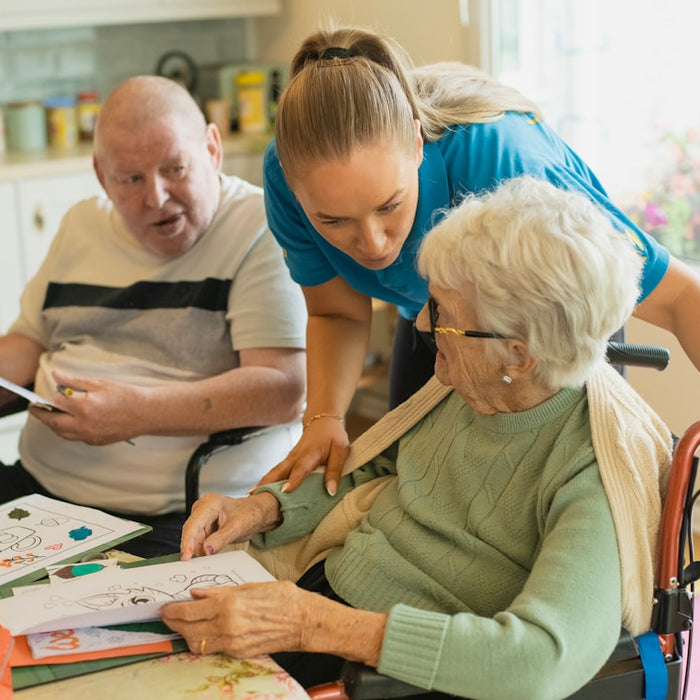 Caregiver assisting elderly couple with coloring
