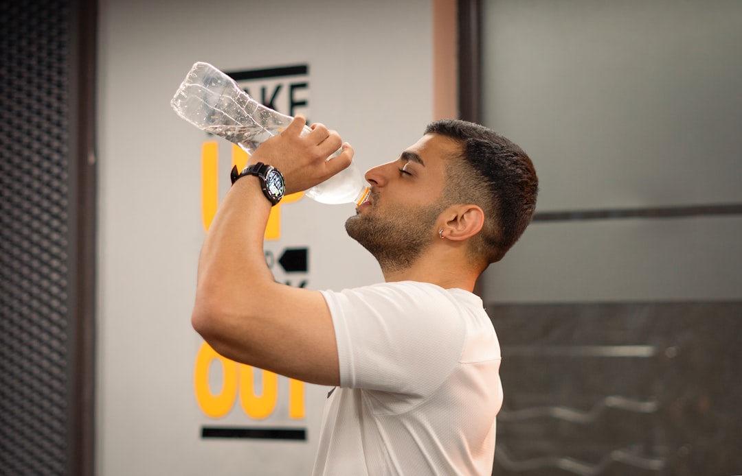 Man drinking water from bottle in gym.