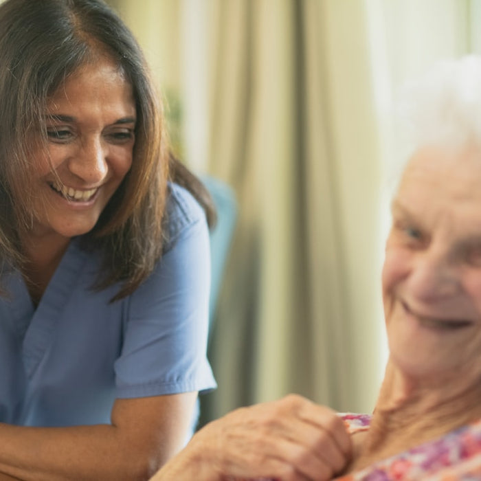Nurse smiling with elderly patient in room