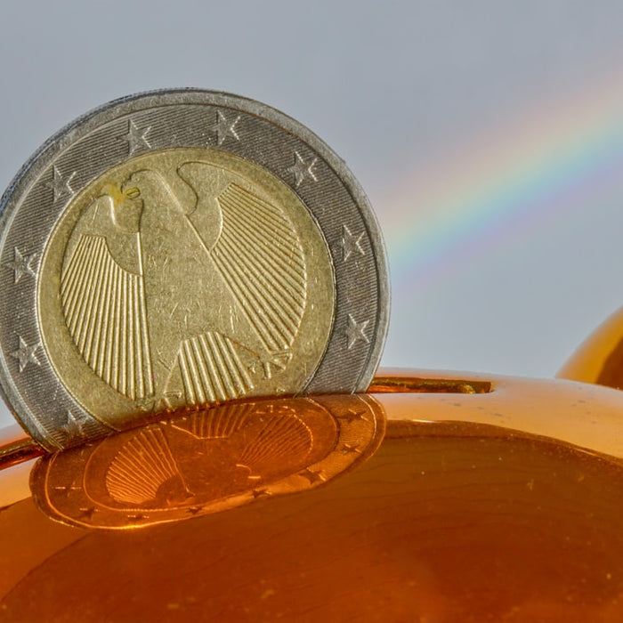 A coin being placed into a golden piggy bank.