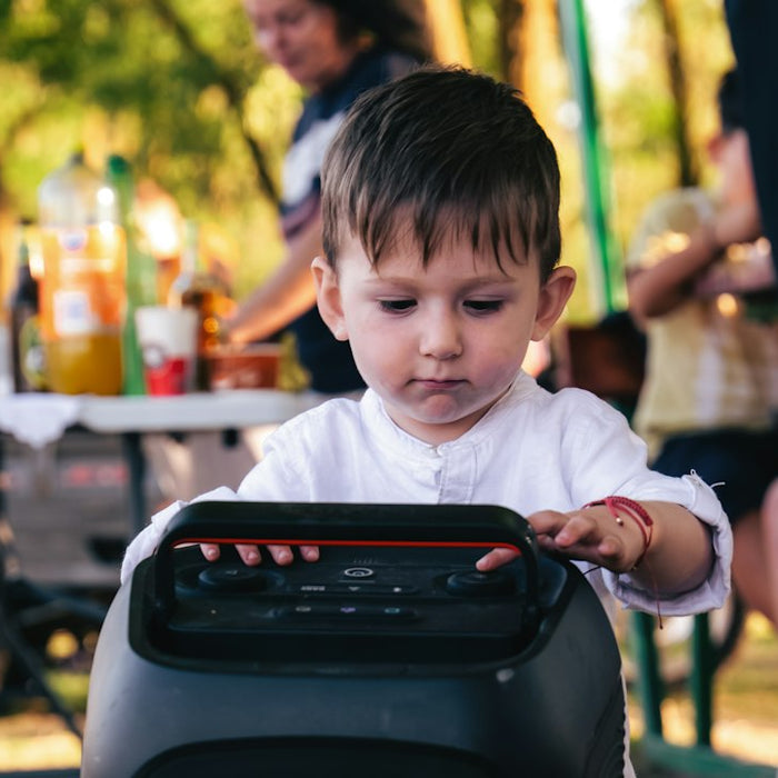 A child touching the controls of a portable speaker outdoors