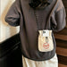 Lightweight Shoulder Phone Bag - A lightweight shoulder phone bag in beige with a drawstring closure and a logo, hanging from a person's shoulder.