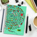 Lancia Full Colour Notebook - Medium - A medium-sized notebook with a spiral binding features a vibrant, abstract design in greens, pinks, and orange.