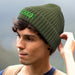 Denali Beanie - An olive green ribbed beanie with a logo, worn by a person with curly hair.