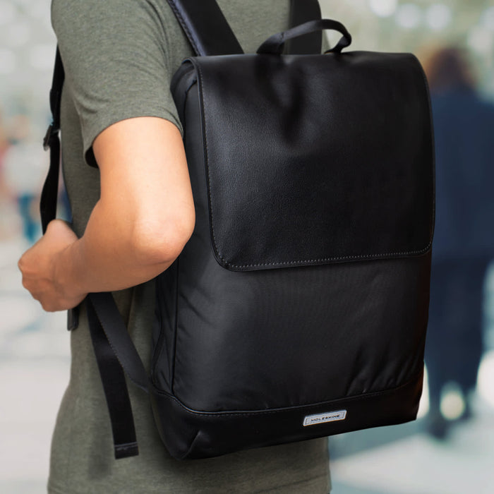 Moleskine Metro Slim Backpack - A black Moleskine Metro Slim Backpack is worn on a person's back, featuring a sleek design and a branding logo.