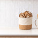 Toma Bread Basket - A bread basket in natural cork and cream fabric, filled with sliced artisan bread, placed on a kitchen counter.
