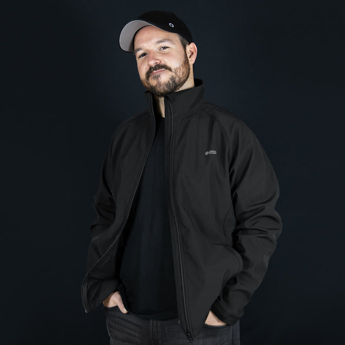 Swiss Peak Urban Softshell Jacket - A man wearing a black Swiss Peak Urban Softshell Jacket with a logo, against a dark background.