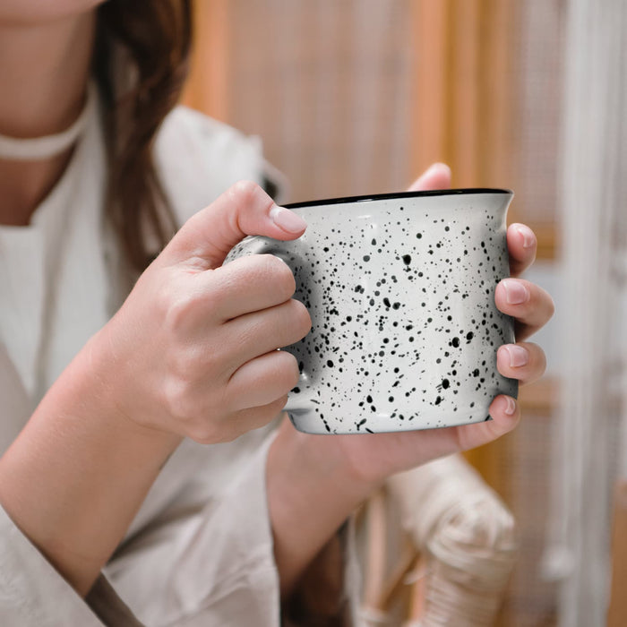 Bendigo Ceramic Mug - A ceramic mug featuring a speckled black and white design, held by a person with one hand. The mug has a contrasting rim.