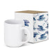 Arista Stackable Coffee Mug - A stackable white coffee mug next to a decorative box featuring blue floral designs. The box has a logo.