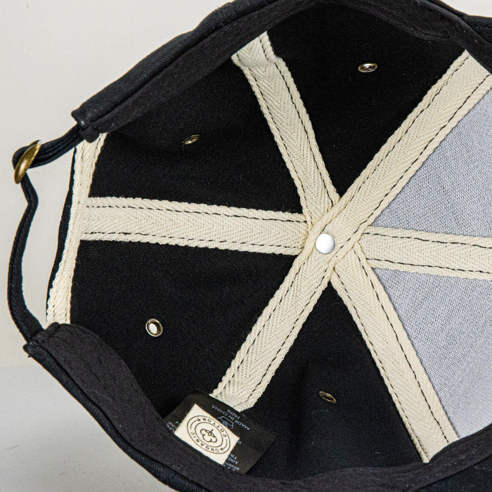 Essence Organic Cap - An organic cap featuring a black exterior with a light-coloured lining and internal stitching details.