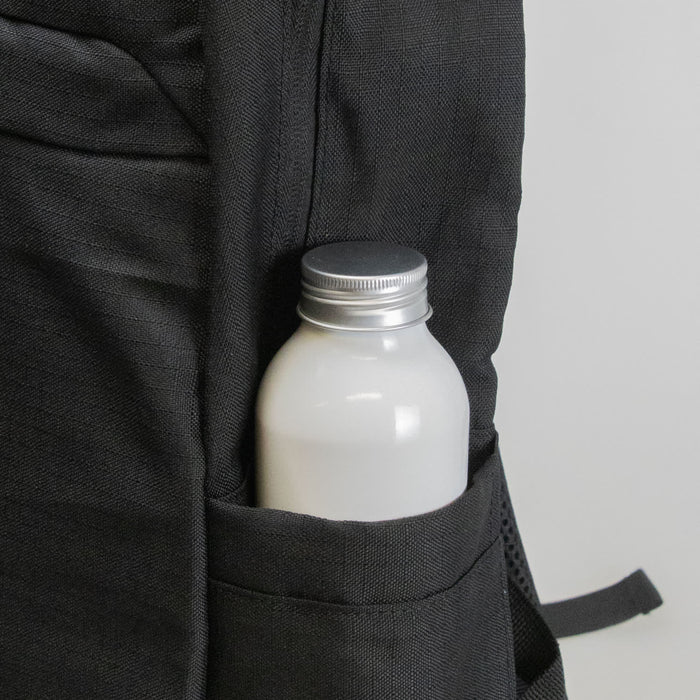Oceana Recycled Backpack - A black backpack pocket holds a silver-capped drink bottle, featuring a textured fabric design.