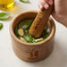 Keepsake Mortar & Pestle - A wooden mortar and pestle filled with fresh basil, garlic, salt, and oil, featuring a logo on the side.