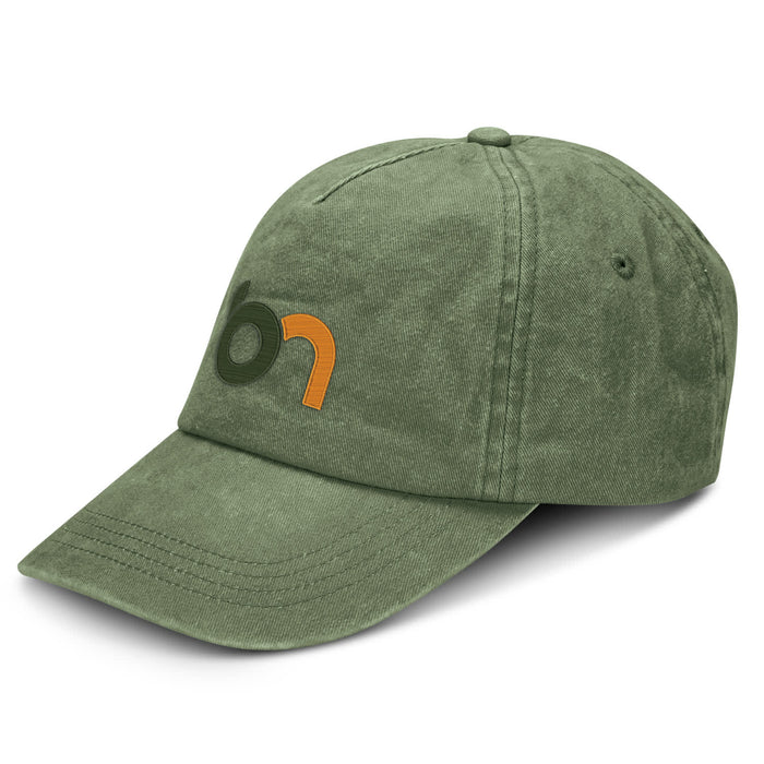 Vintage Washed Cap - A vintage washed cap in olive green with a logo on the front. The cap features a curved brim and textured fabric.