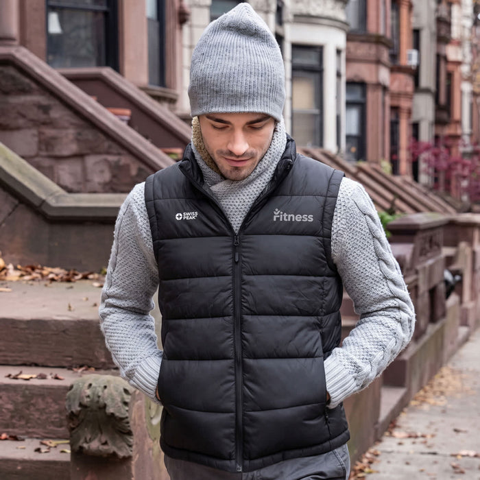 Swiss Peak Urban Unisex Puffer Vest - A black unisex puffer vest worn over a grey sweater, paired with a grey beanie. The vest features a logo.