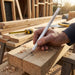 Staedtler Carpenters Pencil - A white carpenter's pencil is being used to mark a wooden plank on a workbench, surrounded by timber.