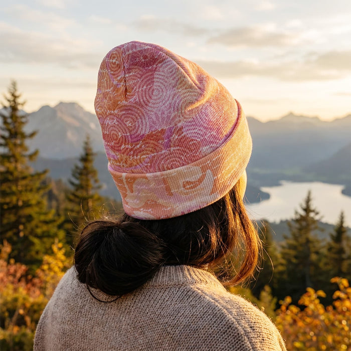 Everest Custom Full Colour Beanie - A full-colour beanie in shades of pink and orange, worn by a person against a scenic mountain backdrop.