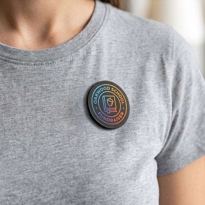 Multi-Functional Magnetic Badge - A person wearing a grey t-shirt with a round, multicoloured badge featuring a logo, attached to the chest area.