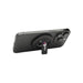 Ain Recycled Plastic Magnetic Phone Stand with Bottle Opener - A magnetic phone stand in black, featuring a bottle opener and a logo, mounted on the back of a smartphone.