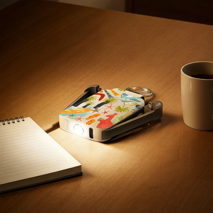 Mini Power Bank with Flashlight - A mini power bank with a colourful design and a flashlight feature on a wooden table beside a mug and notepad.