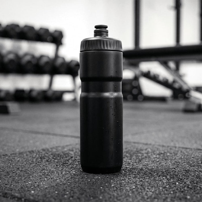 Sprint Sport Bottle 750ml - A drink bottle in black, standing upright on a gym floor with weights in the background.
