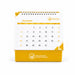 Desk Calendar With Organizer - A desk calendar with a yellow base and a white top, featuring a month grid for December and a logo.