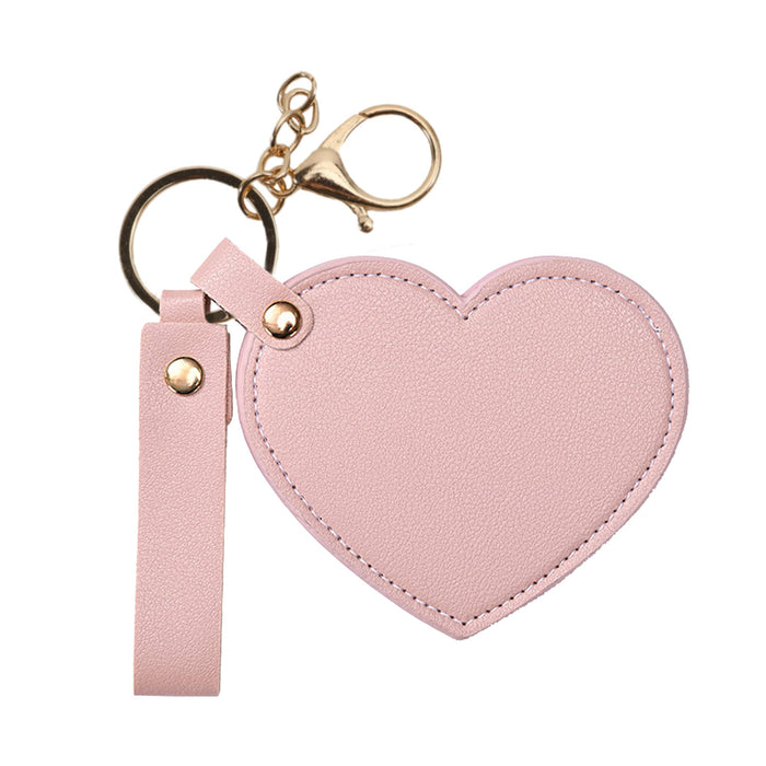 Heart-Shaped Compact Mirror with Keychain - A pink heart-shaped compact mirror with a gold keychain attachment. Includes a strap for easy carrying.