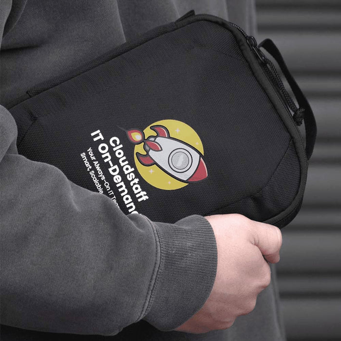 Travel Pack - A black tech case with a logo, featuring a rocket design and a handle, held by a person in a grey hoodie.