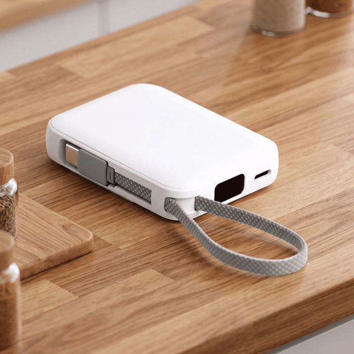 Orbit Magnetic Power Bank 5000mAh - A white power bank with a grey strap sits on a wooden table, featuring a logo on its side.