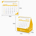 Desk Calendar With Organizer - A yellow desk calendar with an organiser, featuring a spiral top and a triangular base, displaying the month of December.
