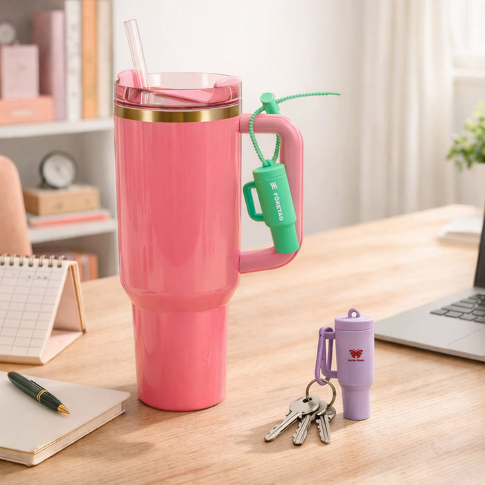 Lip Balm Holder Keychain - A pink drink bottle with a gold rim, alongside a green and purple lip balm holder keychain on a desk.