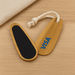 Bamboo Paddle Nail File - A bamboo paddle nail file featuring a black filing surface and a rope loop, with a logo on one side.