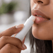 Twist Lip Balm - A twist lip balm in a white container being applied to lips. The person has light skin and natural-looking makeup.