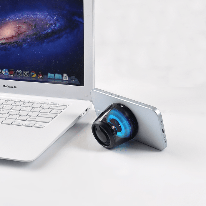 Pacific Magnetic Bluetooth Speaker Stand with RGB LED Light (Stock) - A Bluetooth speaker stand with RGB LED light in black, positioned beside a laptop and a smartphone.