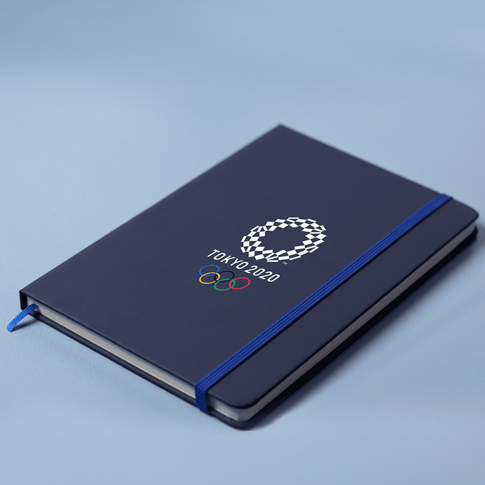 Space A5 Notebook - A navy A5 notebook with an elastic band closure and an Olympic-themed logo on the cover.